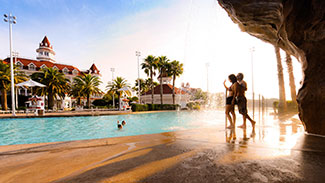 A youbg couple stand by the pool at the Grand Floridian.